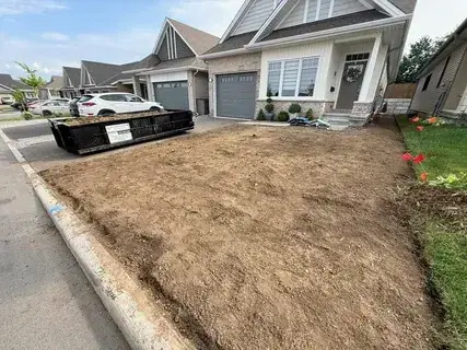 Front yard stripped and rough graded, with an I.D. Construction bin on the driveway