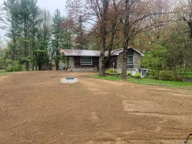 Nivellement brut terminé sur un terrain résidentiel devant une maison