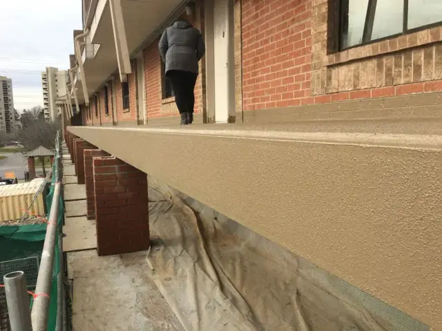 Rive de dalle réparée et recouverte sur la passerelle extérieure d’un immeuble de brique