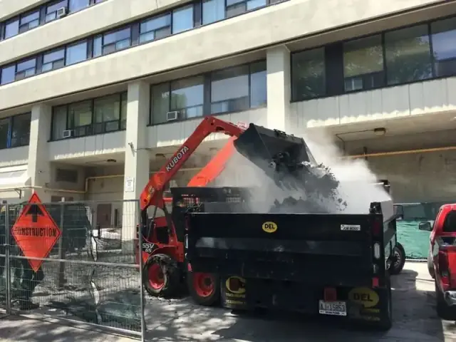 Kubota skid steer loading demolition debris into a dump trailer