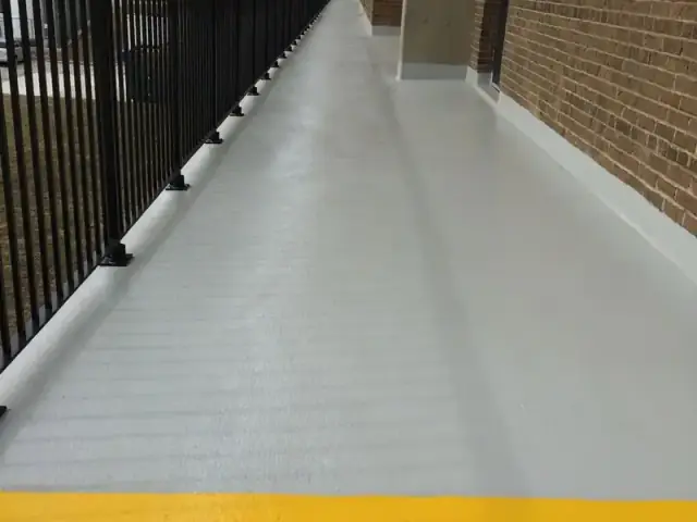 Exterior apartment walkway with a new grey traffic coating and yellow safety line