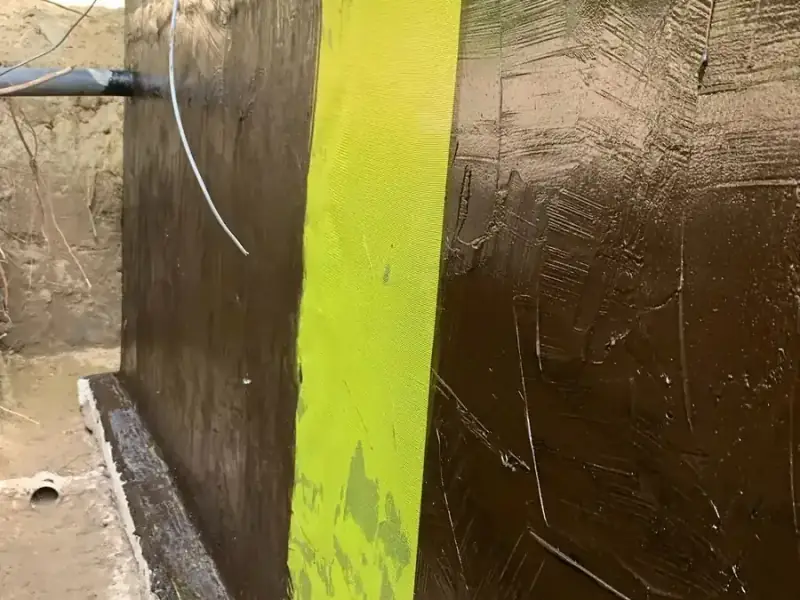 Fluid-applied membrane with reinforcing fabric on an exterior foundation wall