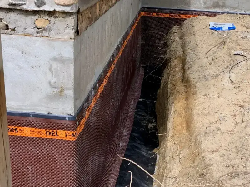 Dimpled drainage board fastened over the membrane on a foundation wall
