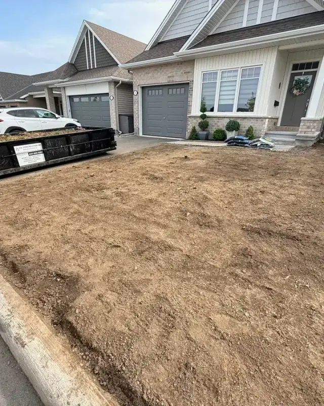 Front yard stripped and rough graded, with an I.D. Construction bin on the driveway