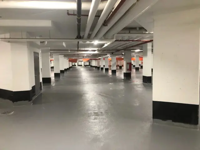 Plancher recouvert et colonnes peintes dans un stationnement souterrain